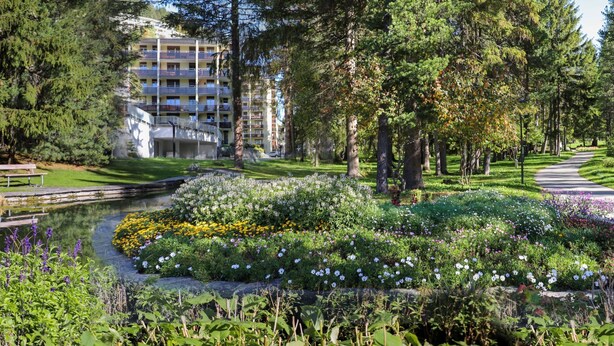 Un hotel con jardín, un estanque y un camino.