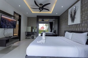 Una habitación de hotel moderna con una cama grande, un televisor de pantalla plana, un ventilador de techo y un cuadro en la pared.