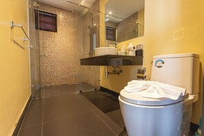 Un baño moderno con ducha de vidrio, inodoro y lavabo con artículos de aseo.
