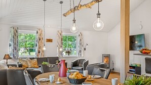 A modern living room with a round wooden table, leather sofas, and a fireplace. - "Guthbrand" - 1.3km from the sea by Interhome (Blåvand)