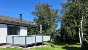 Una casa con porche techado, chimenea y patio cercado.