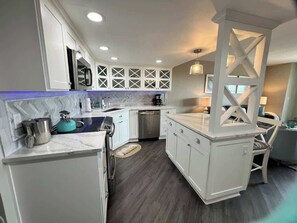A modern kitchen with white cabinetry, a built-in dishwasher, and a kitchen island with seating.