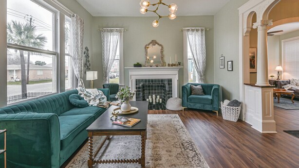 A living room with a fireplace, green sofas, a coffee table, and a chandelier.
