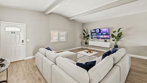 Ein modernes Wohnzimmer mit einem weißen Sofa, einem Couchtisch und einem an der Wand befestigten Flachbildfernseher.