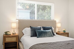 A neatly made bed with a beige headboard, two bedside lamps, and a vintage telephone on a wooden nightstand.