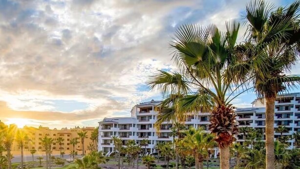 Un campo de golf con palmeras y un hotel al fondo.