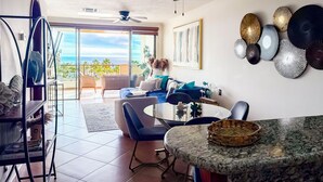 Un amplio espacio de sala con balcón, ventilador de techo y mesa de comedor con cesta.