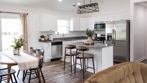 A modern kitchen with white cabinets, a stainless steel refrigerator, and a bar stool area. - Relaxing Retreat Near Bourbon Trail & Horse Country (Cynthiana)