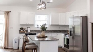 A modern kitchen with white cabinets, a central island, and a stainless steel refrigerator. - Relaxing Retreat Near Bourbon Trail & Horse Country (Cynthiana)