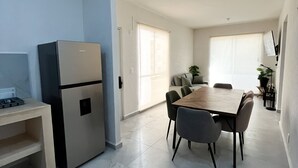 A modern kitchen with a built-in refrigerator, a dining table with chairs, and a large window providing natural light.