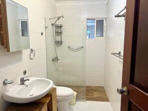 A bathroom with a white sink, toilet, and shower.
