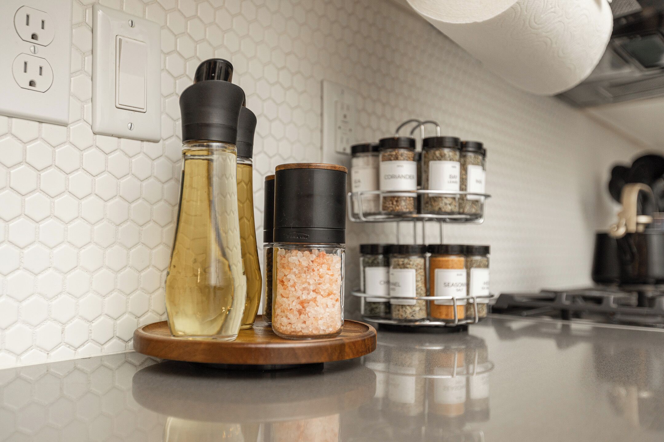 Un plan de travail de cuisine avec des salières et des poivrières, une bouteille d’huile et un étagère à épices.