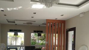 Ein geräumiges Zimmer mit einem Chandelier, einer Essecke und einer Sitzecke mit einem weißen Stuhl und einer Couch.