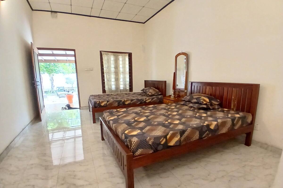 A bedroom with two wooden beds, a large mirror, and a door leading to a balcony.