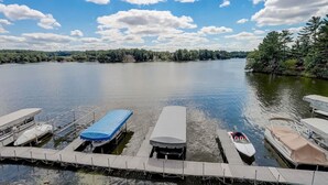 A dock with several boats, a clear sky, and a calm lake surrounded by trees.