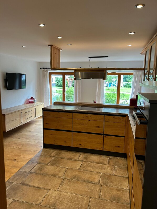Une cuisine moderne dotée de meubles en bois, d’un îlot central et d’une grande fenêtre offrant une vue sur l’extérieur.