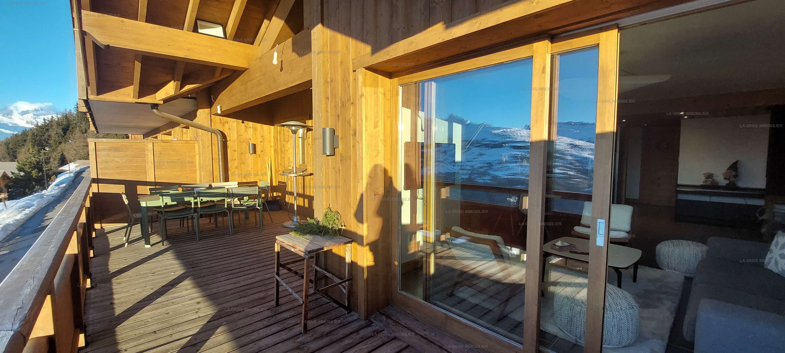 Une terrasse en bois avec des meubles d’extérieur, une table et des chaises.