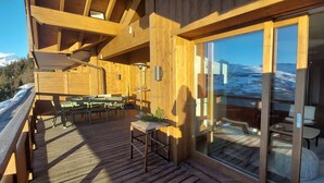 Een houten terras met tuinmeubilair, een tafel en stoelen.