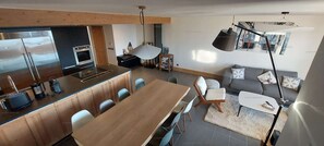 A modern kitchen with a central island, dining area with chairs, and a living space with a sofa and a coffee table. - Paradiski, calm and sunny vallandry (LANDRY)