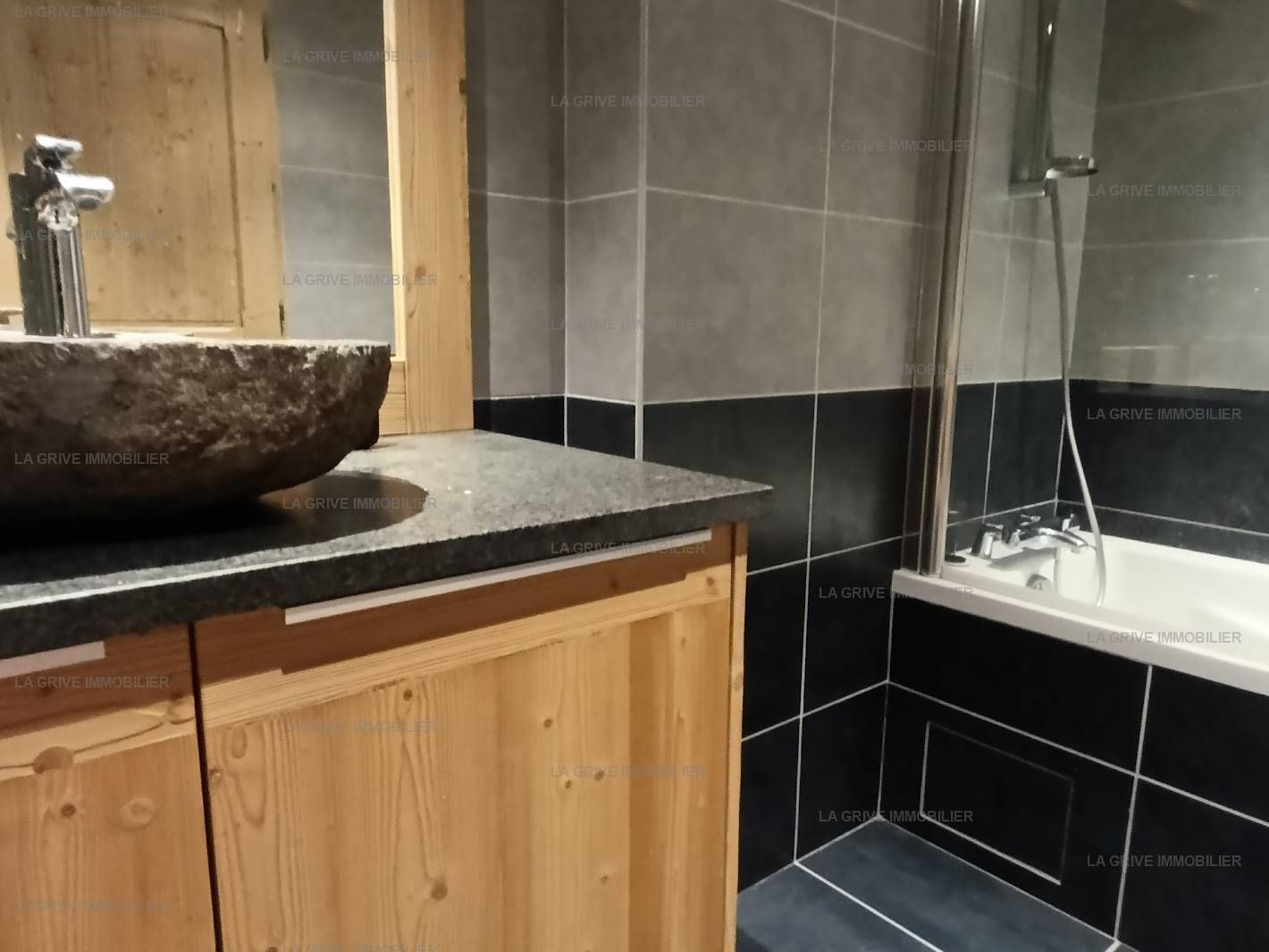 Ein Badezimmer mit einem Steinkonstruktion als Waschbecken, Holzschränken und einer Duschkabine.