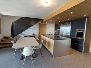 A modern kitchen with a central island, built-in appliances, and a dining area with a table and chairs.