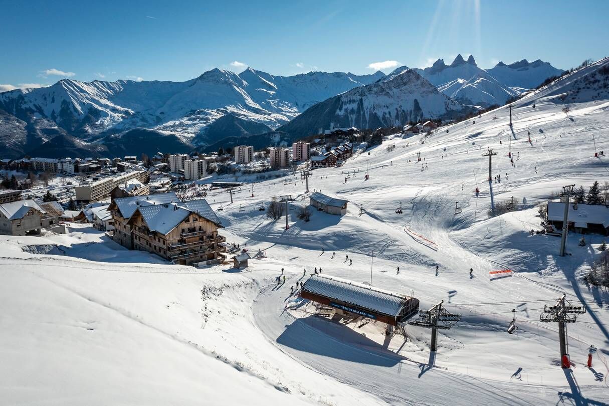 Een met sneeuw bedekte wintersportplaats met gebouwen, skiliften en een berg op de achtergrond.