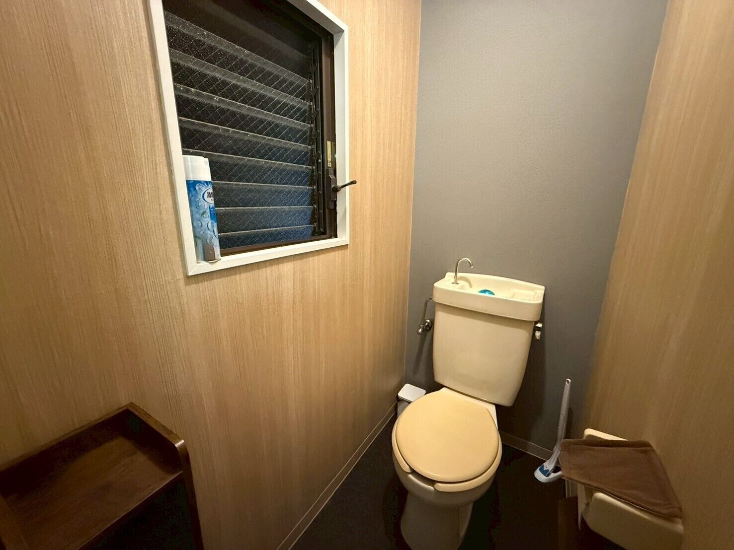 Ein kleines, kompaktes Badezimmer mit Toilette, einem Fenster mit Jalousien und einem Waschbecken.