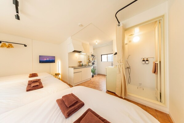 A hotel room with two beds, a kitchenette, and a shower area. - NEST BASE IKEBUKURO (Tokyo)