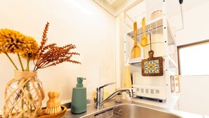 A kitchen with a stainless steel sink, a spice rack, and a decorative vase with dried flowers.