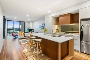 Une cuisine moderne dotée d’un îlot central, d’appareils électroménagers en acier inoxydable et offrant une vue sur la ville.
