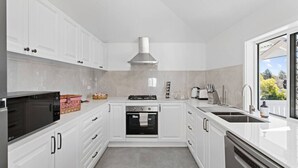 A modern kitchen with white cabinetry, a built-in oven, a gas stove, and a dishwasher.