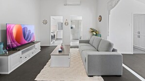 Una sala de estar moderna con televisor de pantalla plana, sofá gris y una mesita de centro.