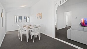 Una habitación amplia con comedor, un sofá gris y una escalera que sube a otro nivel.