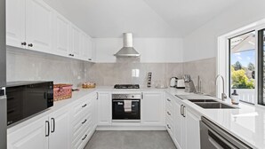 Una cocina moderna con armarios blancos, horno empotrado, estufa, microondas y lavavajillas.
