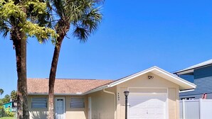 A two-story house with a garage, a well-maintained lawn, and a palm tree.