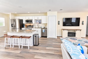 A modern kitchen with white cabinets, stainless steel appliances, and a central island with bar stools.