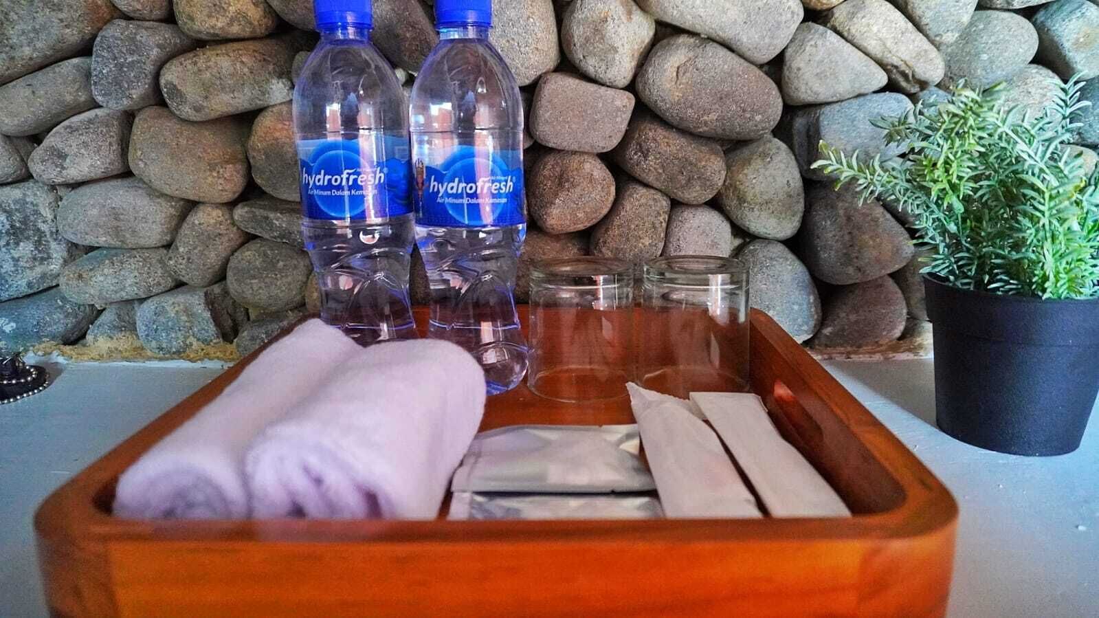 A wooden tray with a towel, two bottles of water, and a glass.