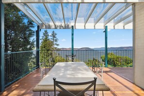 Un espace extérieur aménagé, abrité et doté de tables et de chaises, offrant une vue panoramique sur un lac et des montagnes.