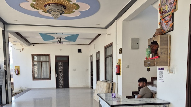 A spacious lobby with a marble reception desk, a ceiling fan, and a decorative chandelier. - Shyam Niwas Guest House (Danta Ramgarh)
