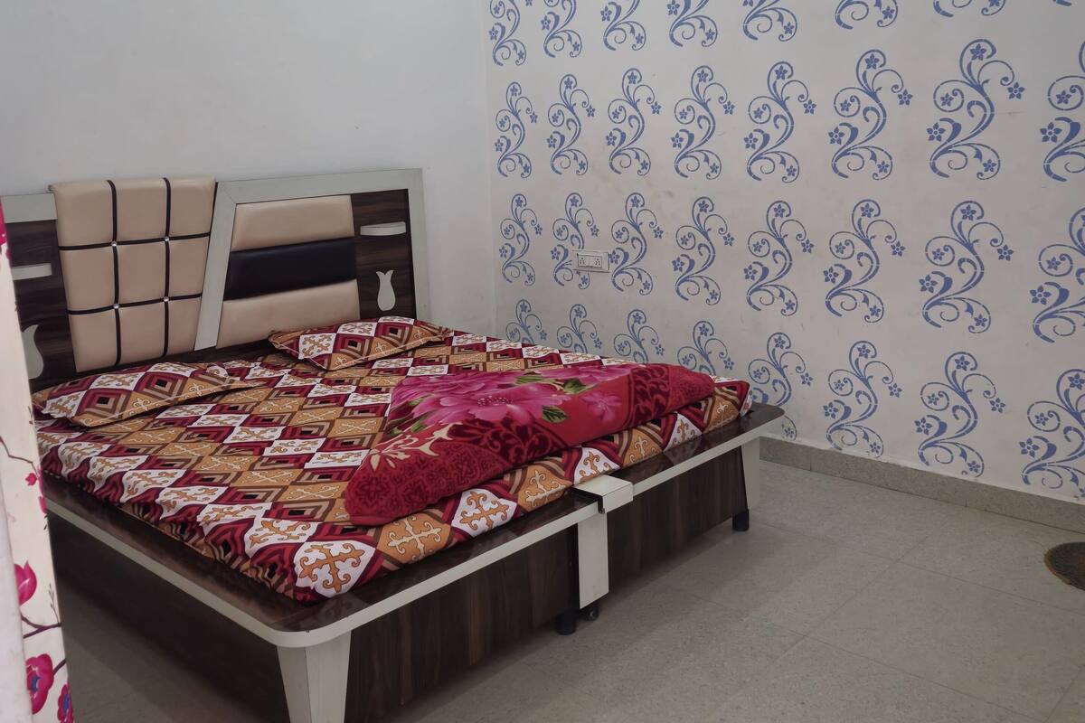 Ein Schlafzimmer mit Bett, Kopfstütze, Wandklimaanlage und ornamentalem Wandpapier.