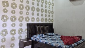 A bedroom with a bed, a nightstand, a ceiling fan, and a wall-mounted air conditioner. - Shyam Niwas Guest House (Danta Ramgarh)