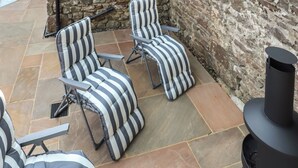 Un patio con mobiliario exterior a rayas y un muro de piedra.
