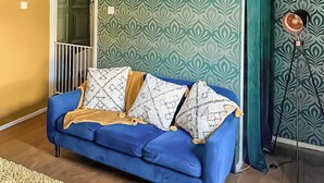 Un canapé bleu agrémenté de coussins à motifs, un plancher en bois et un papier peint à motifs.