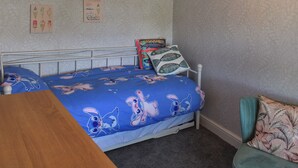 Une chambre à coucher comprenant un lit, une chaise, une table en bois et deux éléments de décoration murale.