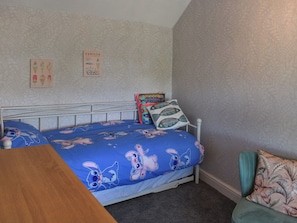 A bedroom with a bed, a chair, a wooden table, and two wall decorations. - 2 bedroom accommodation in Pakefield, near Lowestoft (Pakefield, near Lowestoft)