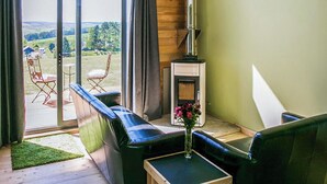 A cozy living room with a fireplace, a sofa, and a view of the outdoors. - Modern comfort meets rugged wilderness at Tarset Tor’s unique glamping retreat. (Hexham, near Bellingham)