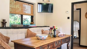 A cozy room with a wooden table, a sofa, a television, and a window with a view of greenery. - 1 bedroom accommodation in Ruswarp, near Whitby (Ruswarp, near Whitby)