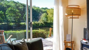 A room with a large sliding glass door leading to a garden, a sofa, a lamp, and a small table. - 1 bedroom accommodation in Ruswarp, near Whitby (Ruswarp, near Whitby)