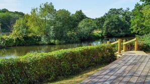 A wooden deck overlooking a river with dense greenery and trees. - 1 bedroom accommodation in Ruswarp, near Whitby (Ruswarp, near Whitby)
