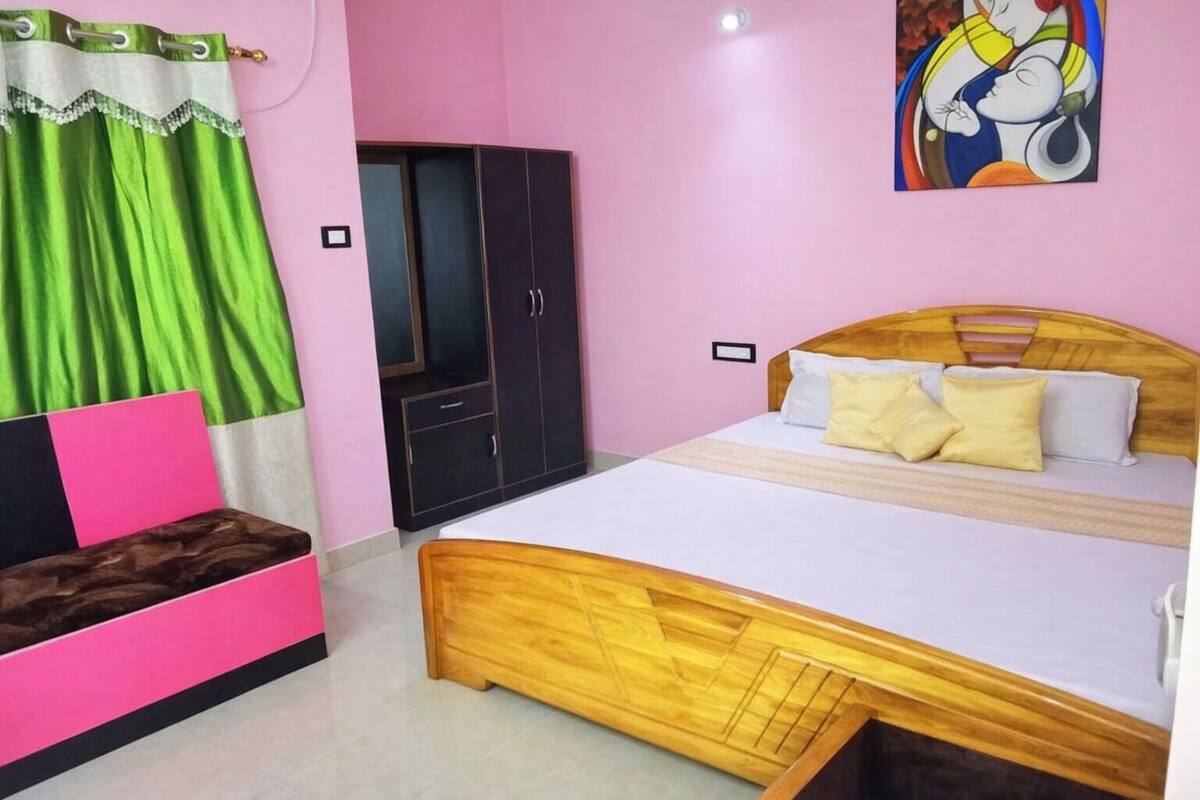 A bedroom with a bed, a wardrobe, a green curtain, and a painting on the wall.
